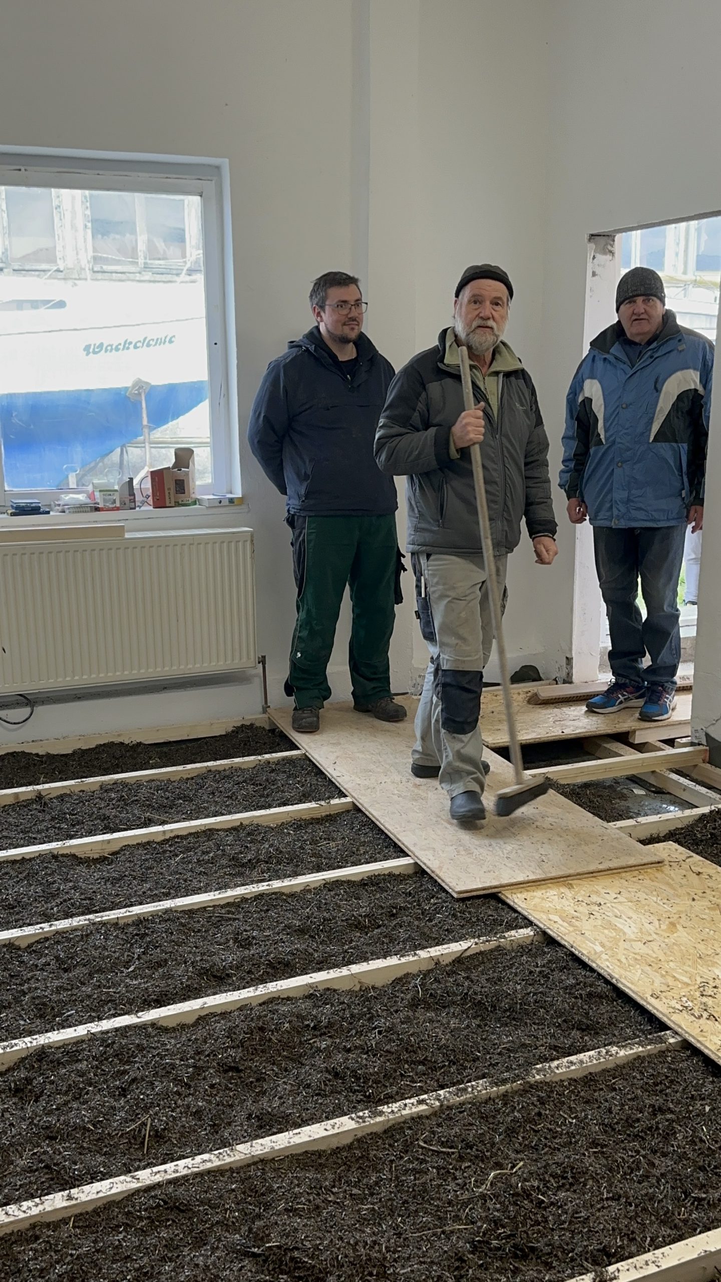 Fertig eingebrachte Seegrassch&uuml;ttung zwischen den Deckenbalken, dar&uuml;ber OSB-Platten als Laufsteg