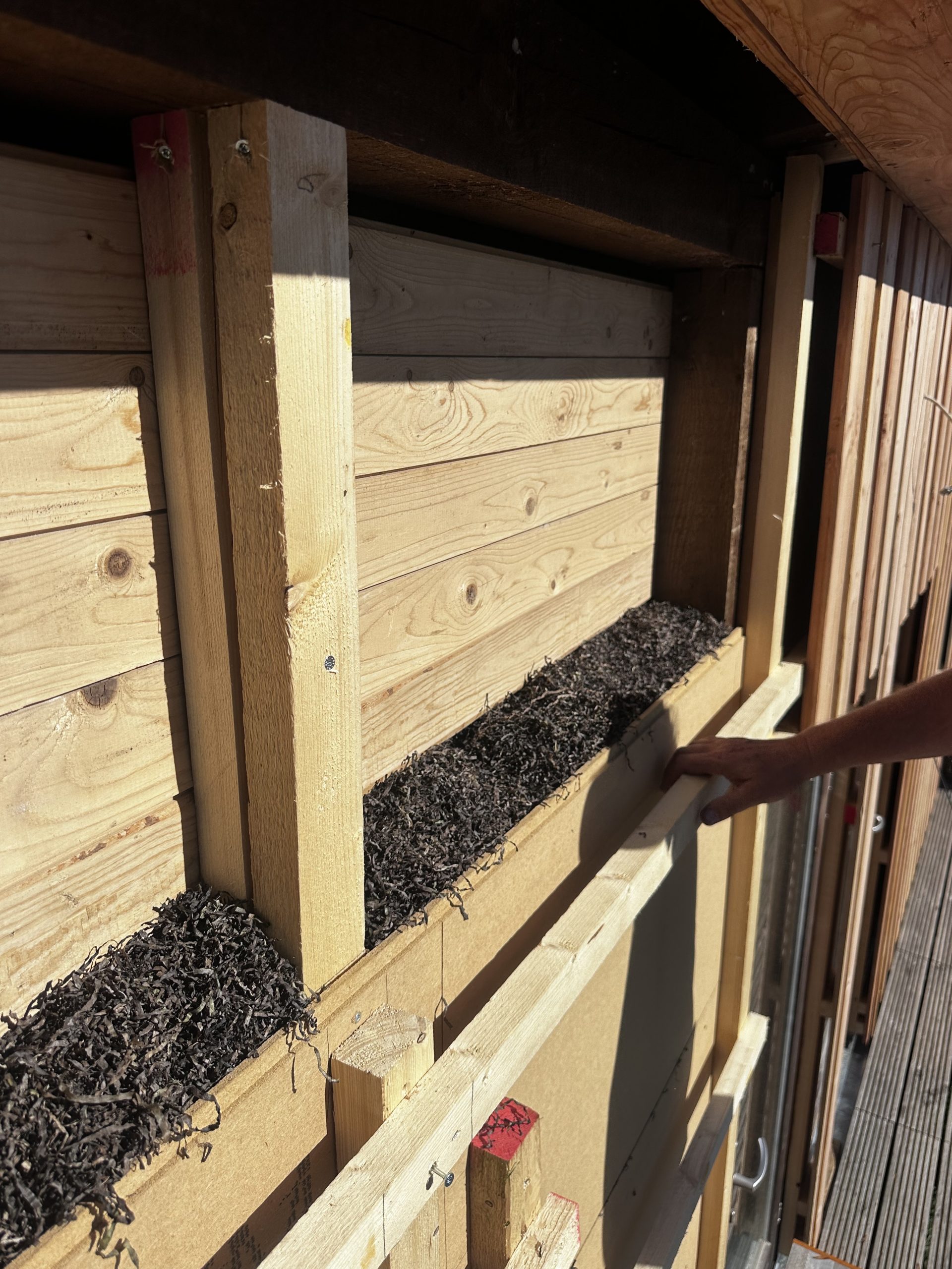 Seegras wird in das offene St&auml;nderwerk einer Fassade gestopft