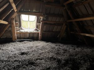 Dicke Seegrasschüttung auf dem Dachboden eines Altbaus, Licht fällt durch ein Rundfenster